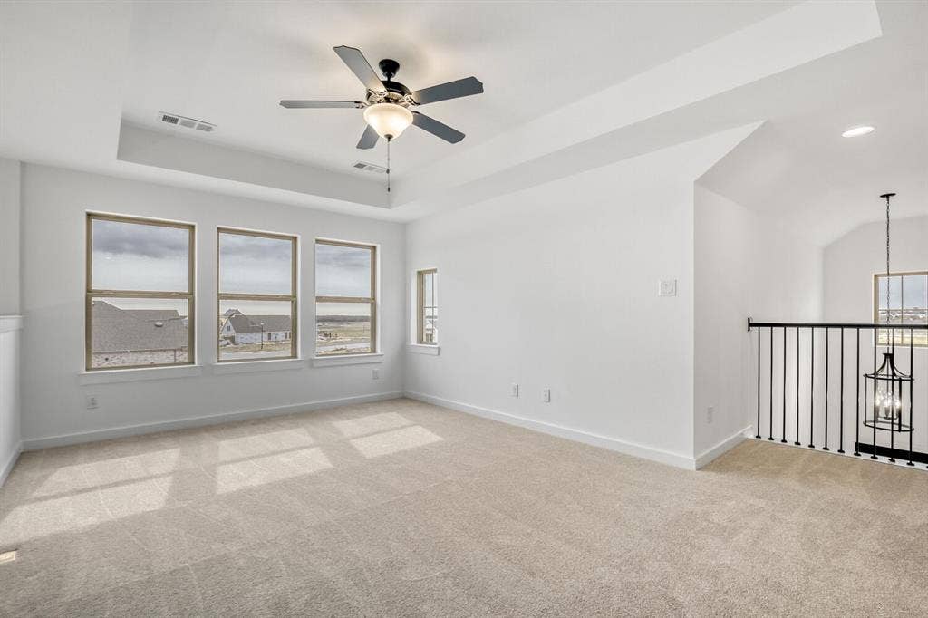2228 Prickly Cactus Drive, Forney, TX 75126 Unfurnished room featuring a tray ceiling, light colored carpet, ceiling fan, and suspended lighting