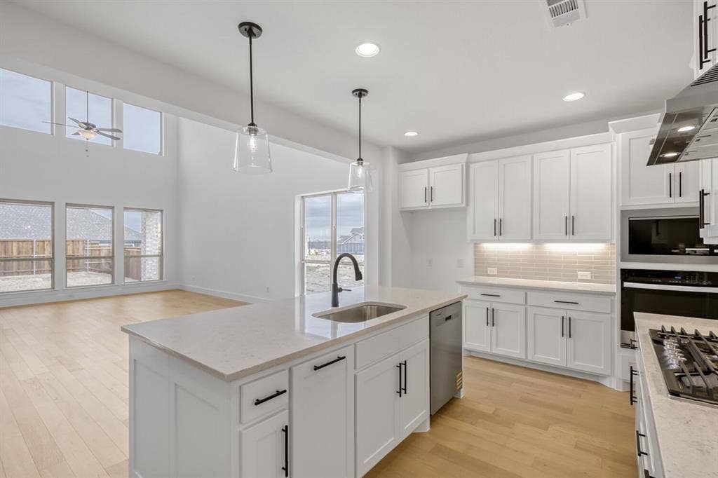 2228 Prickly Cactus Drive, Forney, TX 75126 Kitchen with hanging light fixtures, white cabinetry, tasteful backsplash, stainless steel appliances, and light wood finished floors