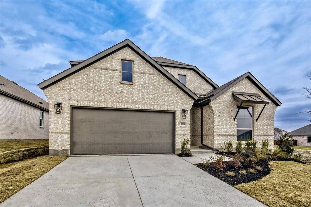 2228 Prickly Cactus Drive, Forney, TX 75126 French country inspired facade featuring concrete driveway, brick siding, and an attached garage