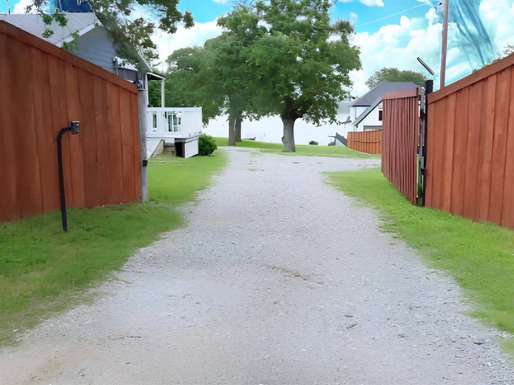 7130 Briar Road, Azle, TX 76020 Gravel pathway framed by wooden fences, leading towards a body of water