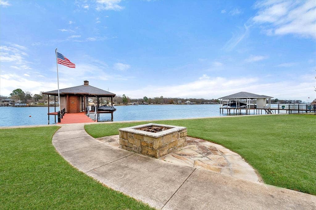 110 Northwood Place, Enchanted Oaks, TX 75156 Dock with an outdoor fire pit, boat lift, a yard, and a water view