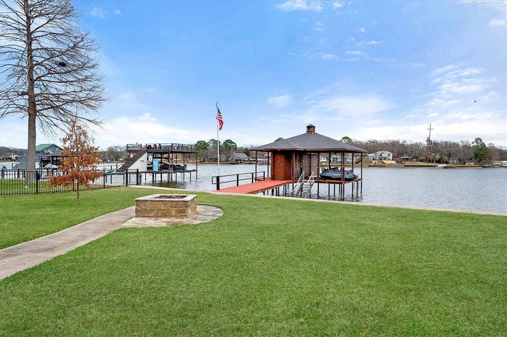 110 Northwood Place, Enchanted Oaks, TX 75156 Dock with boat lift, a lawn, and an outdoor fire pit