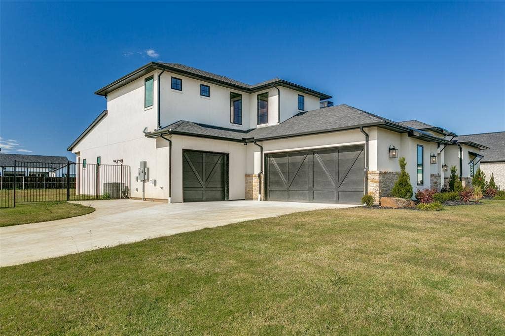 View of front of house featuring stucco siding, driveway, stone siding, and an attached garage