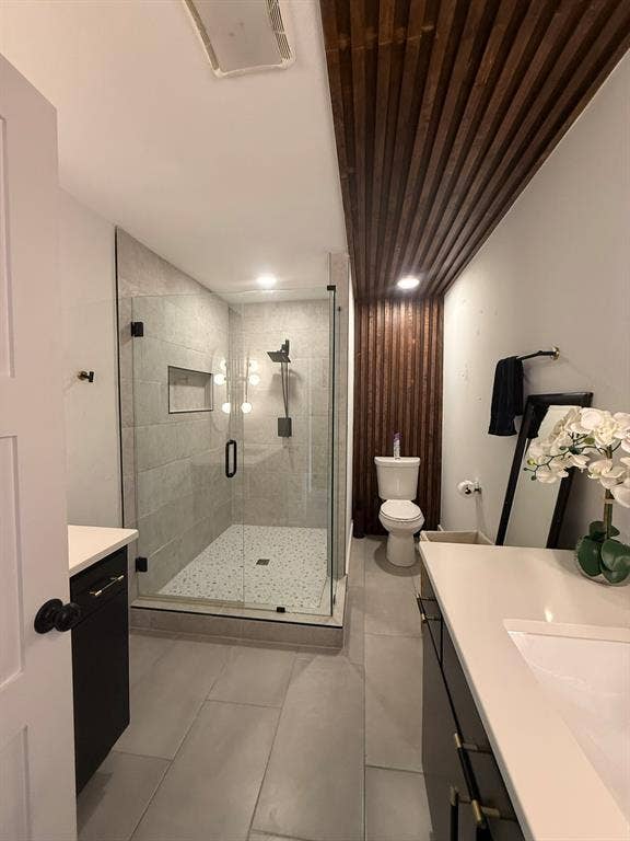 Full bath featuring a stall shower, vanity, and light tile patterned floors