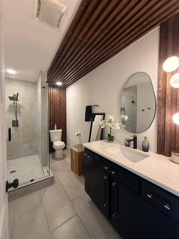 Full bath with a shower stall, vanity, and light tile patterned flooring