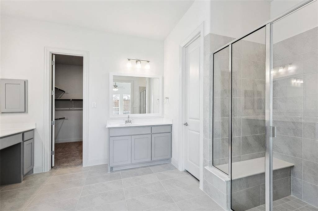 313 Trinity Court, Shady Shores, TX 76208 Bathroom featuring vanity, a stall shower, a spacious closet, light tile patterned floors, and a ceiling fan