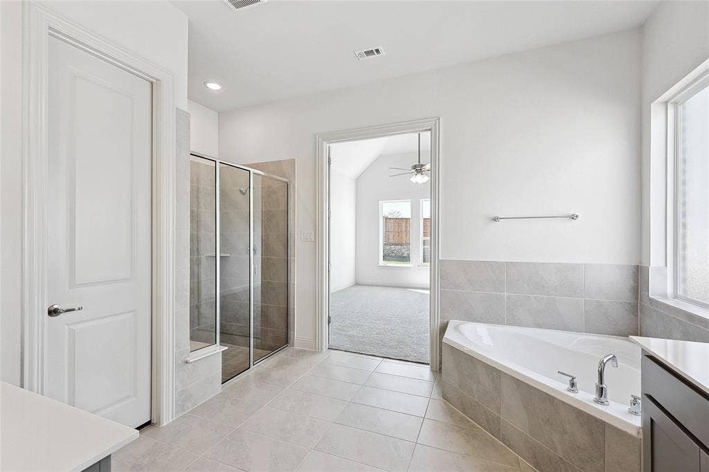 313 Trinity Court, Shady Shores, TX 76208 Bathroom with vanity, a garden tub, a shower stall, light tile patterned floors, and a ceiling fan