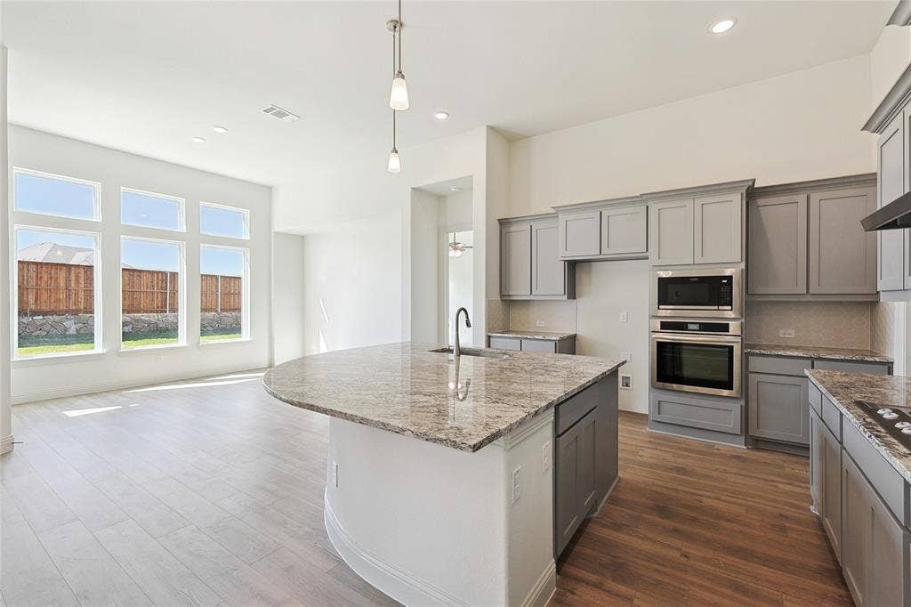 313 Trinity Court, Shady Shores, TX 76208 Kitchen featuring gray cabinets, light stone counters, pendant lighting, stainless steel appliances, and recessed lighting