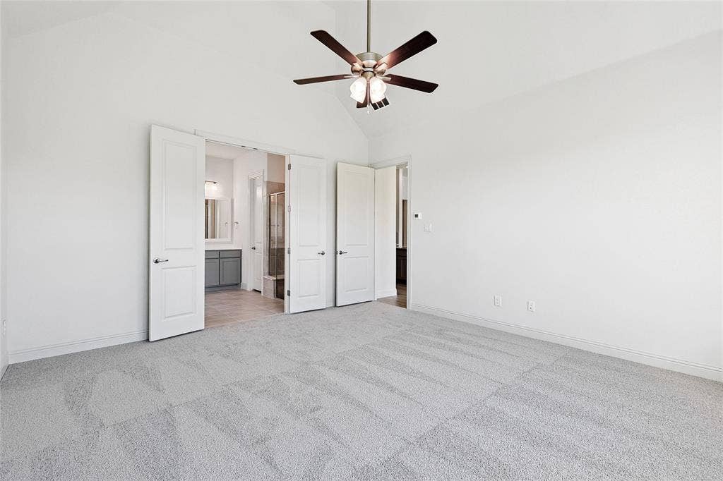 313 Trinity Court, Shady Shores, TX 76208 Unfurnished bedroom featuring high vaulted ceiling, light carpet, ceiling fan, and ensuite bath