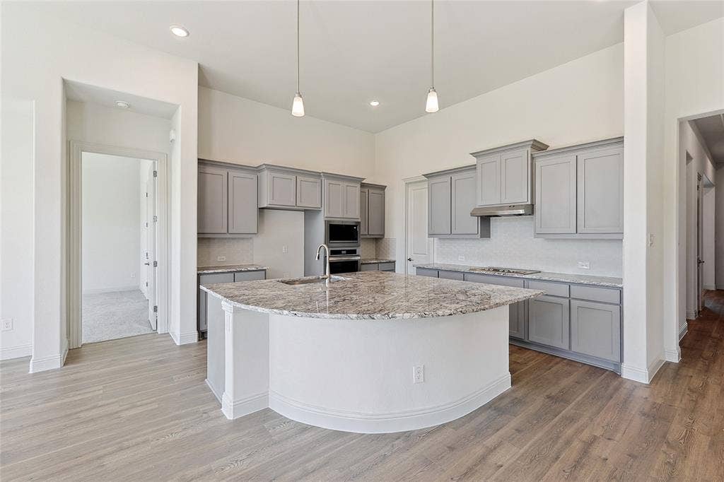 313 Trinity Court, Shady Shores, TX 76208 Kitchen with gray cabinets, decorative light fixtures, light stone countertops, light wood-style flooring, and recessed lighting