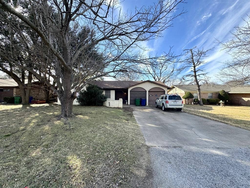 317 N Trail Street, Crowley, TX 76036 Single story home featuring concrete driveway, an attached garage, a front yard, and brick siding