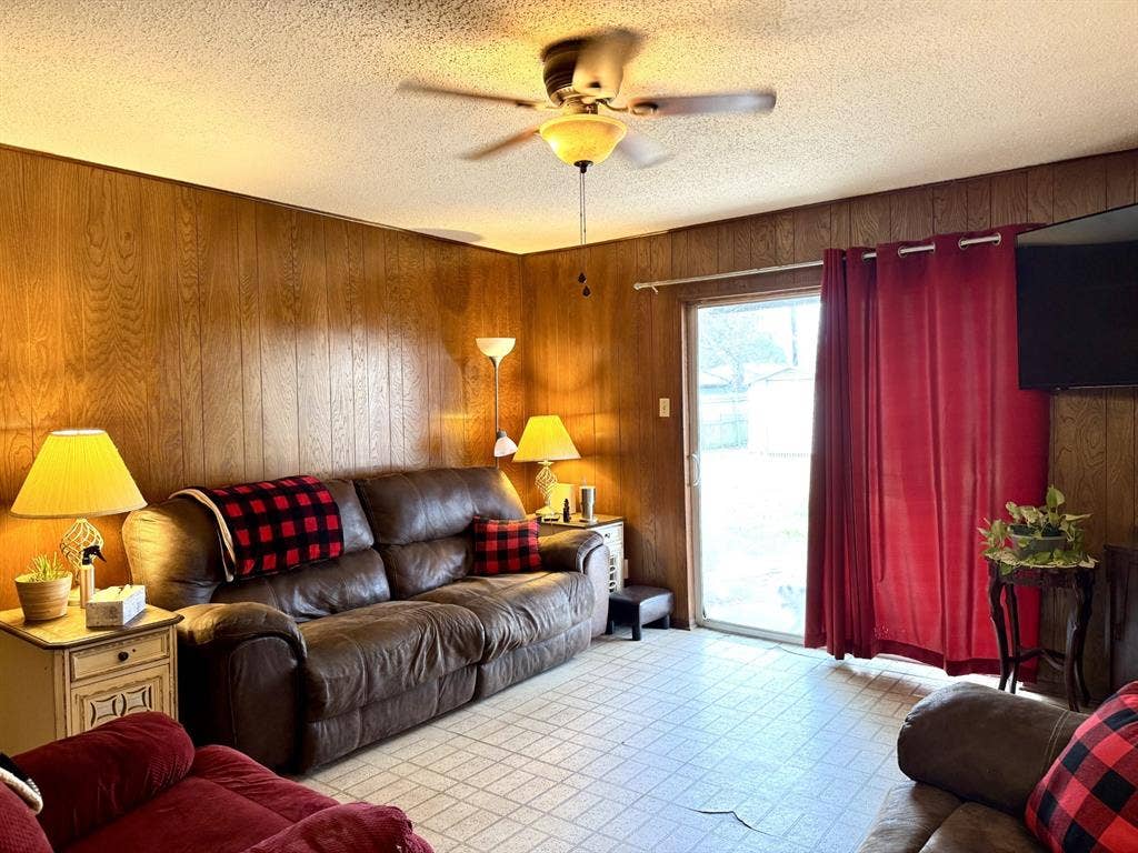317 N Trail Street, Crowley, TX 76036 Living area featuring wood walls, a ceiling fan, and a textured ceiling