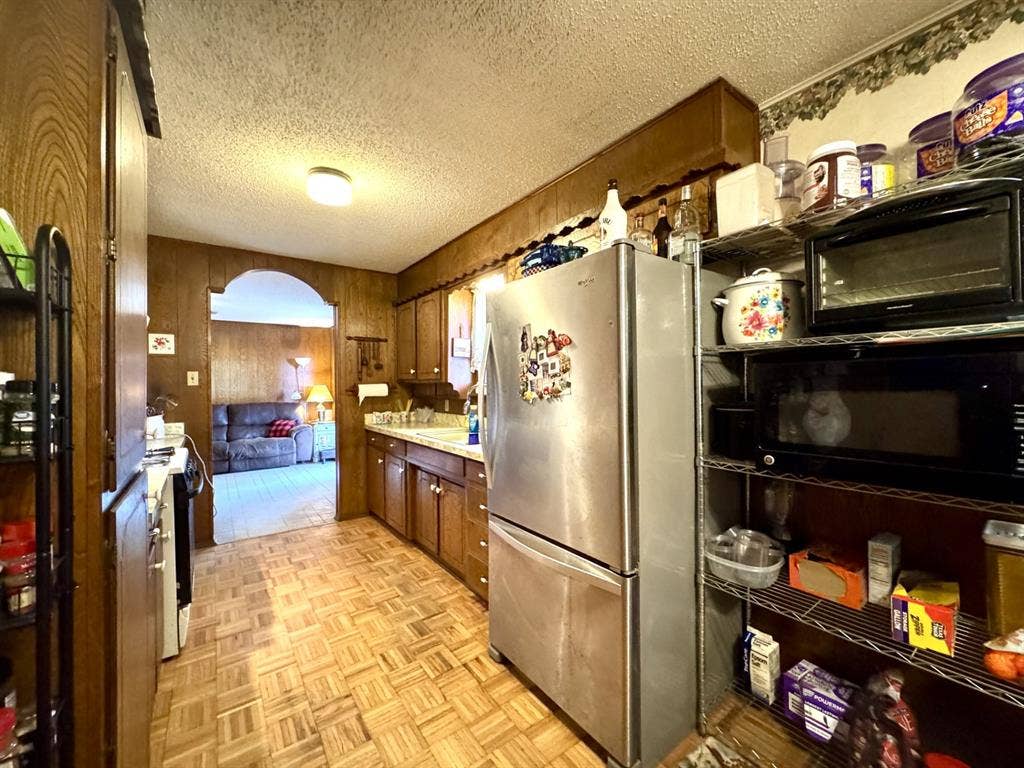 317 N Trail Street, Crowley, TX 76036 Kitchen featuring a textured ceiling, light countertops, freestanding refrigerator, black microwave, and stove