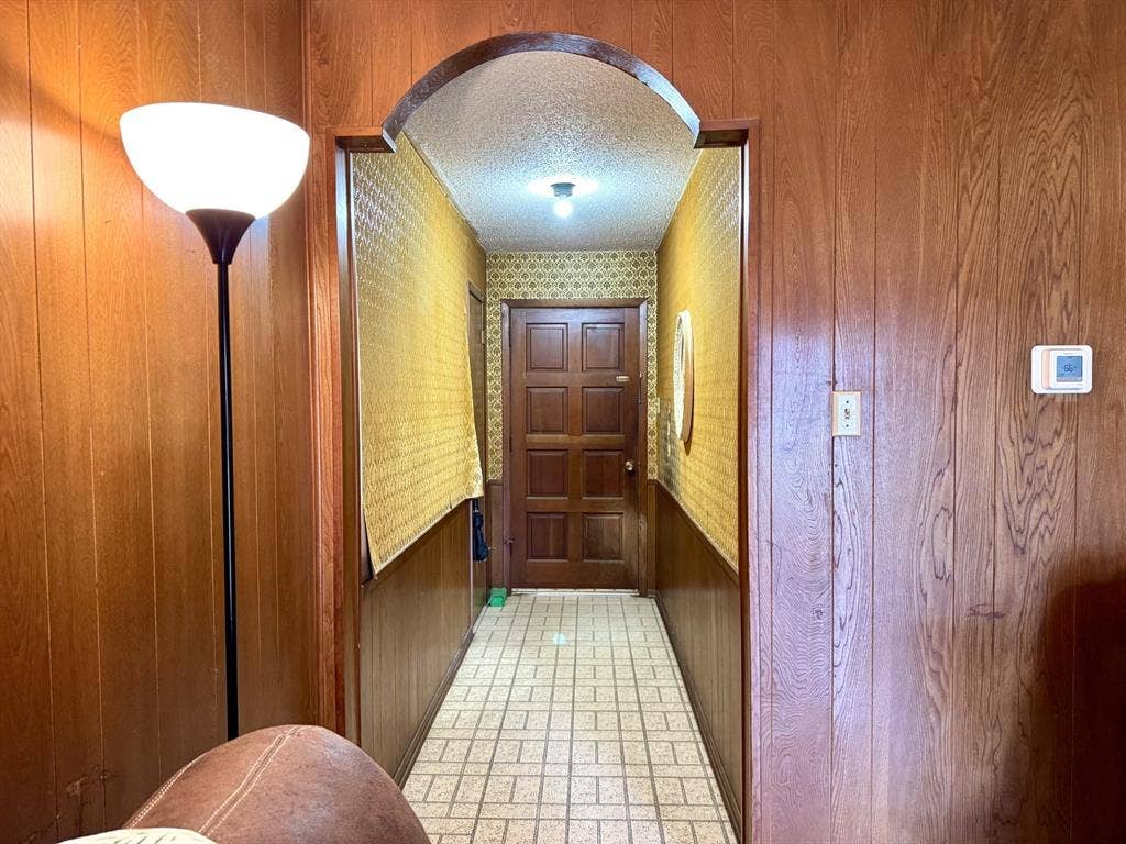317 N Trail Street, Crowley, TX 76036 Doorway to outside featuring wooden walls, a textured ceiling, and arched walkways