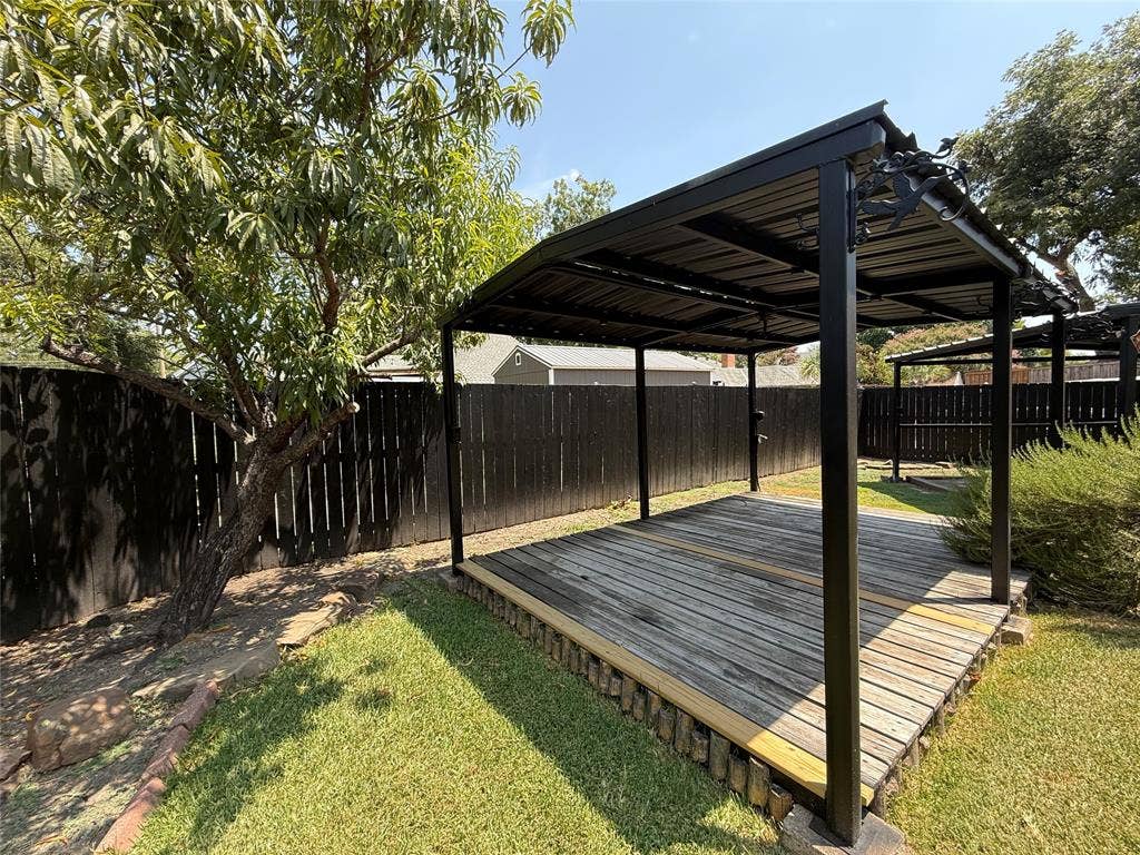 6018 Raleigh Drive, Garland, TX 75044 Expansive backyard featuring a covered outdoor living structure, a wood-plank deck, and a mature tree