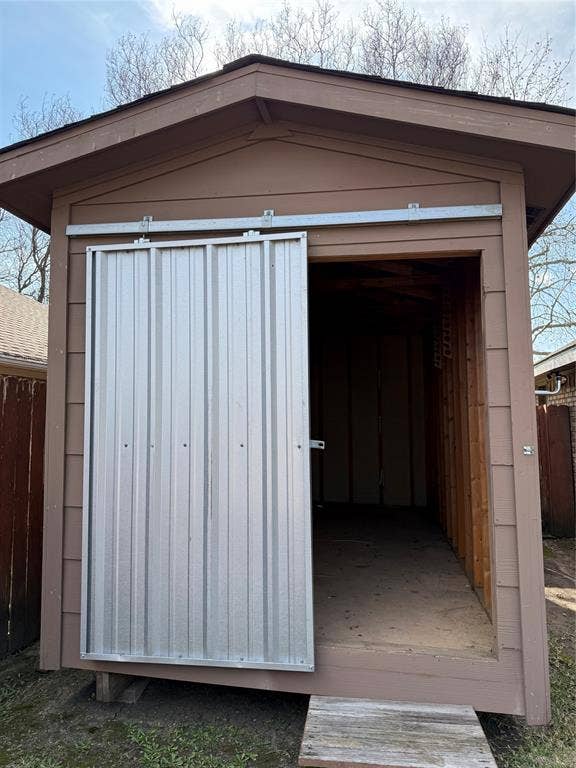 6018 Raleigh Drive, Garland, TX 75044 Brown-painted wood-sided shed featuring a corrugated metal sliding door and a built-in wooden ramp