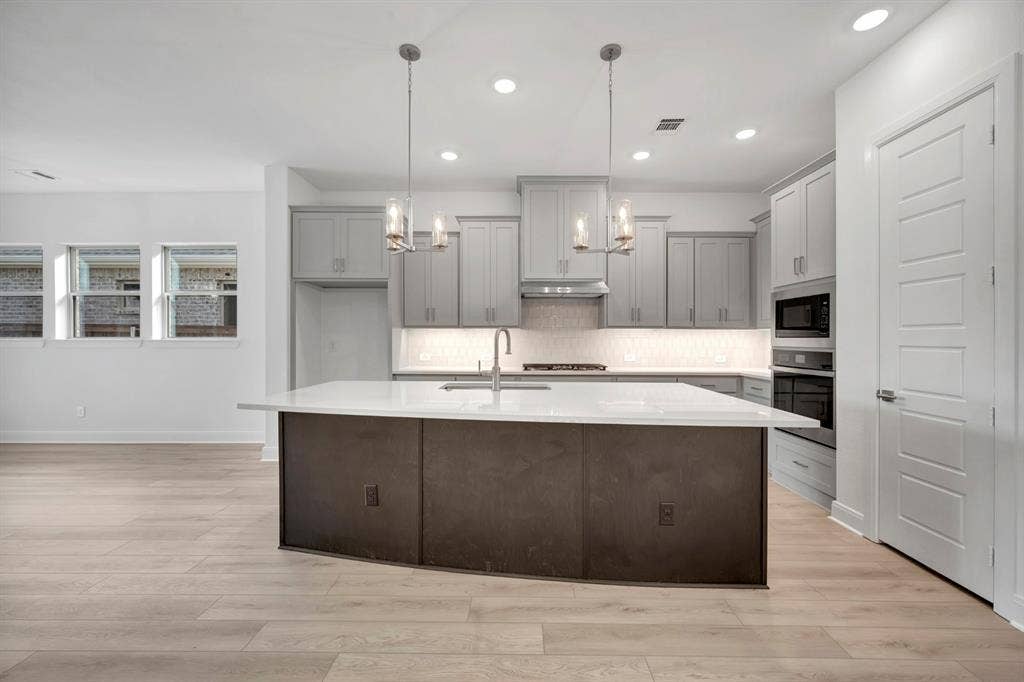 2079 Emerald Grove Lane, Arlington, TX 76005 Kitchen with gray cabinets, light wood finished floors, and a center island with sink