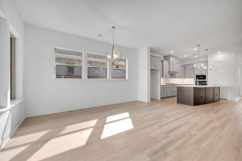 2079 Emerald Grove Lane, Arlington, TX 76005 Kitchen featuring a chandelier, light wood finished floors, and a kitchen island with sink