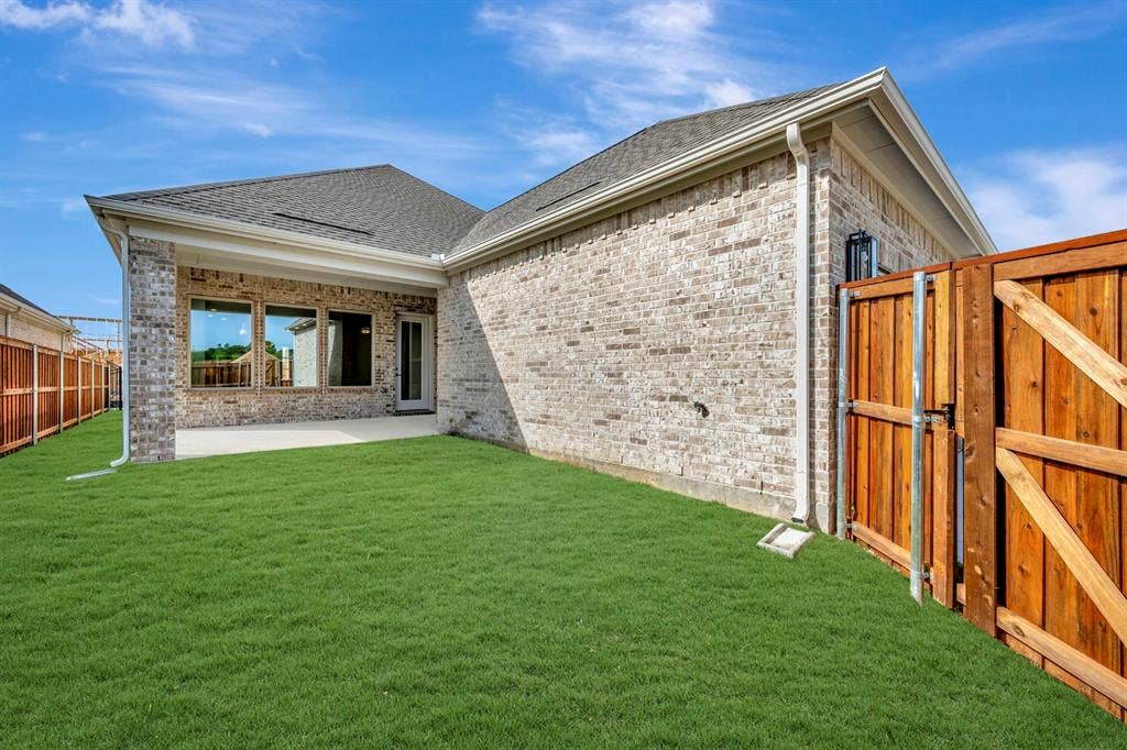 2079 Emerald Grove Lane, Arlington, TX 76005 Back of property with a patio area, a shingled roof, brick siding, and a gate