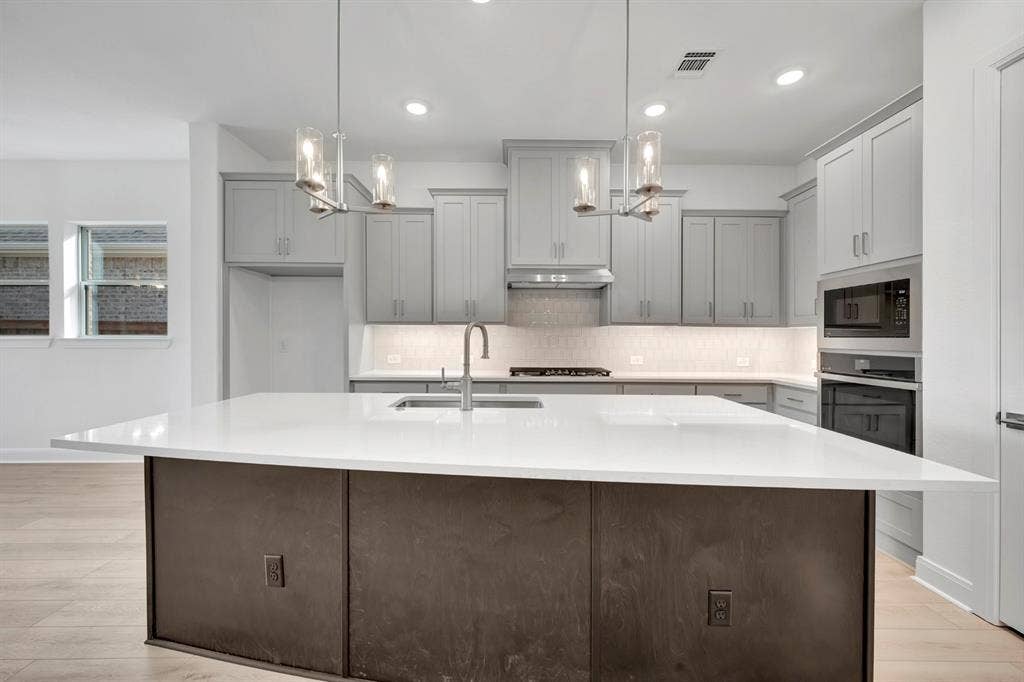 2079 Emerald Grove Lane, Arlington, TX 76005 Kitchen with an island with sink, gray cabinets, light wood finished floors, and light stone counters