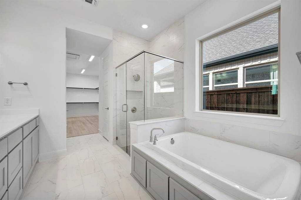 2079 Emerald Grove Lane, Arlington, TX 76005 Bathroom featuring a spacious closet, a marble finish shower, light marble finish floors, vanity, and a bath
