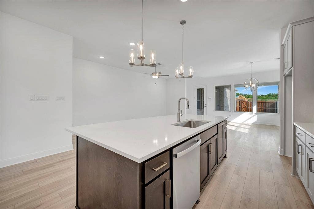 2079 Emerald Grove Lane, Arlington, TX 76005 Kitchen with hanging lights, stainless steel dishwasher, light wood-style flooring, and a center island with sink