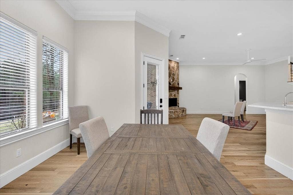 5182 Bayshore Drive, Athens, TX 75752 Dining space featuring arched walkways, crown molding, light wood-type flooring, a fireplace, and recessed lighting
