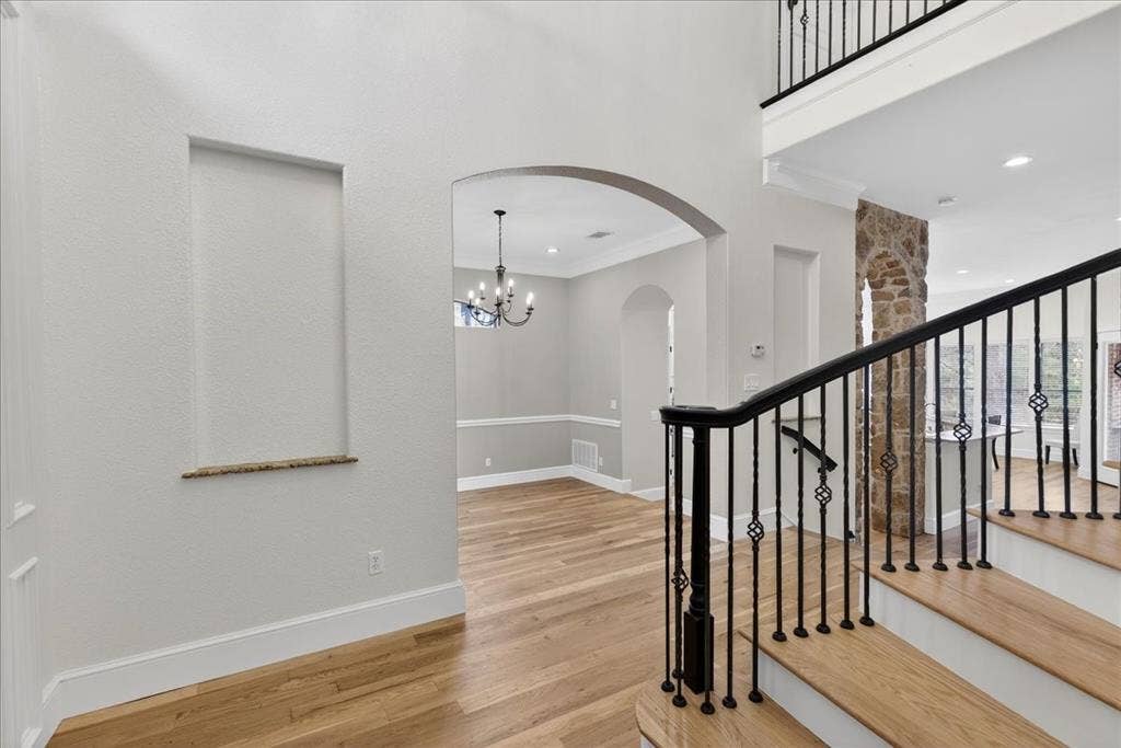 5182 Bayshore Drive, Athens, TX 75752 Stairs featuring wood finished floors, arched walkways, crown molding, suspended lighting, and a high ceiling