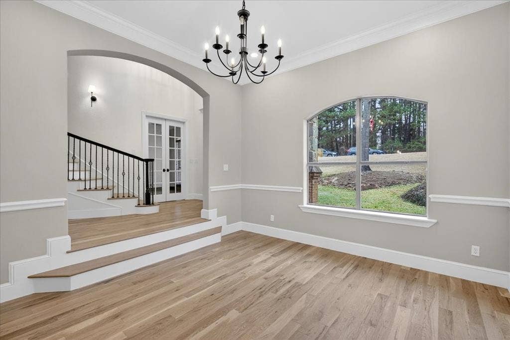 5182 Bayshore Drive, Athens, TX 75752 Unfurnished dining area featuring arched walkways, ornamental molding, light wood-style floors, suspended lighting, and french doors