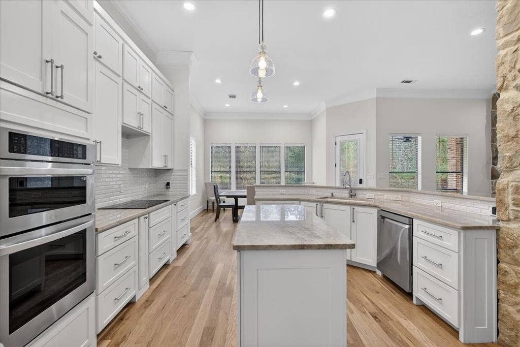 5182 Bayshore Drive, Athens, TX 75752 Kitchen featuring stainless steel appliances, white cabinets, pendant lighting, crown molding, and a kitchen island