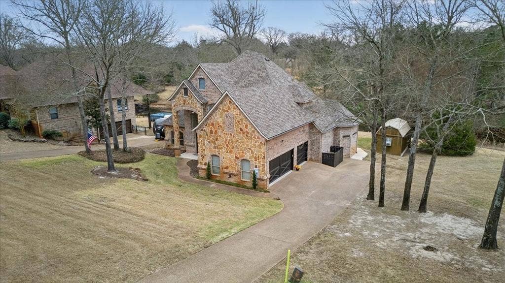 5182 Bayshore Drive, Athens, TX 75752 View of front of property with stone siding, a front lawn, driveway, a storage unit, and a garage