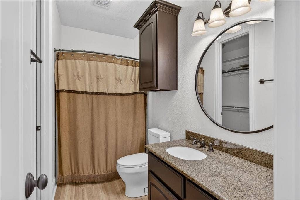 5182 Bayshore Drive, Athens, TX 75752 Bathroom with vanity, a shower with shower curtain, light wood-style flooring, a walk in closet, and a textured wall