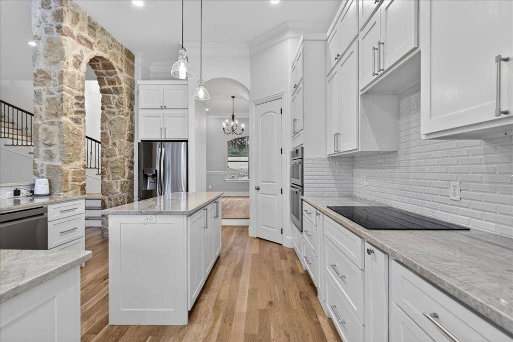 5182 Bayshore Drive, Athens, TX 75752 Kitchen with arched walkways, white cabinetry, ornamental molding, light wood-type flooring, and stainless steel appliances