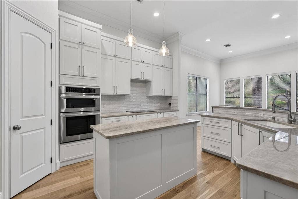 5182 Bayshore Drive, Athens, TX 75752 Kitchen with crown molding, stainless steel double oven, backsplash, light stone counters, and light wood-type flooring