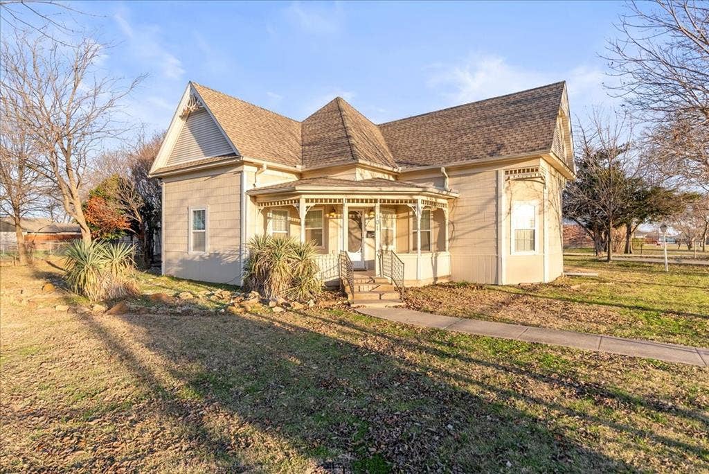101 N 7th Street, Krum, TX 76249 Victorian-style house featuring a front lawn, roof with shingles, and covered porch