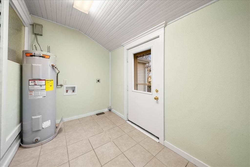 101 N 7th Street, Krum, TX 76249 Washroom with water heater, lofted ceiling, hookup for an electric dryer, light tile patterned floors, and washer hookup