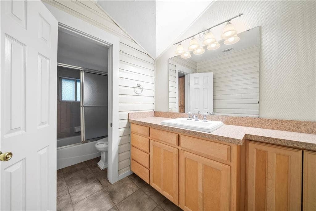101 N 7th Street, Krum, TX 76249 Full bath with vanity, combined bath / shower with glass door, and dark tile patterned floors