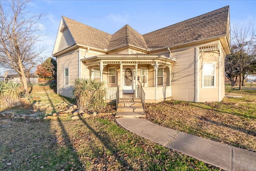 101 N 7th Street, Krum, TX 76249 Victorian home featuring a shingled roof and a porch
