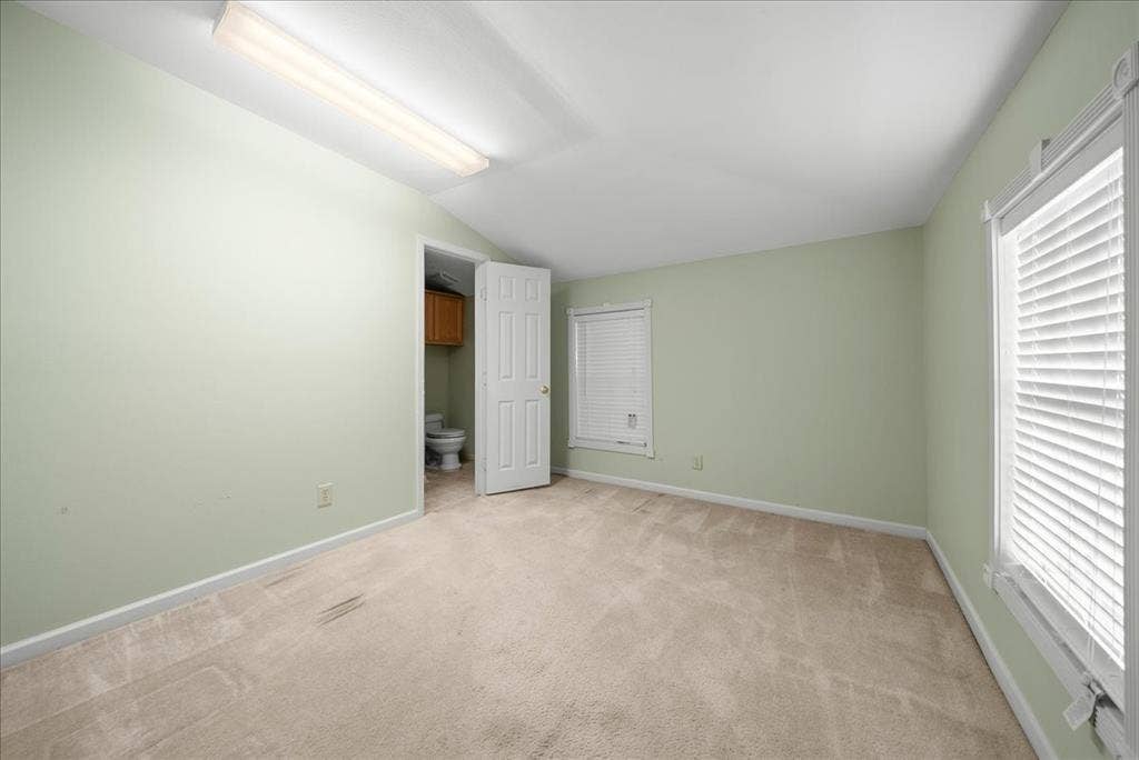 101 N 7th Street, Krum, TX 76249 Unfurnished bedroom featuring light colored carpet, lofted ceiling, and ensuite bathroom