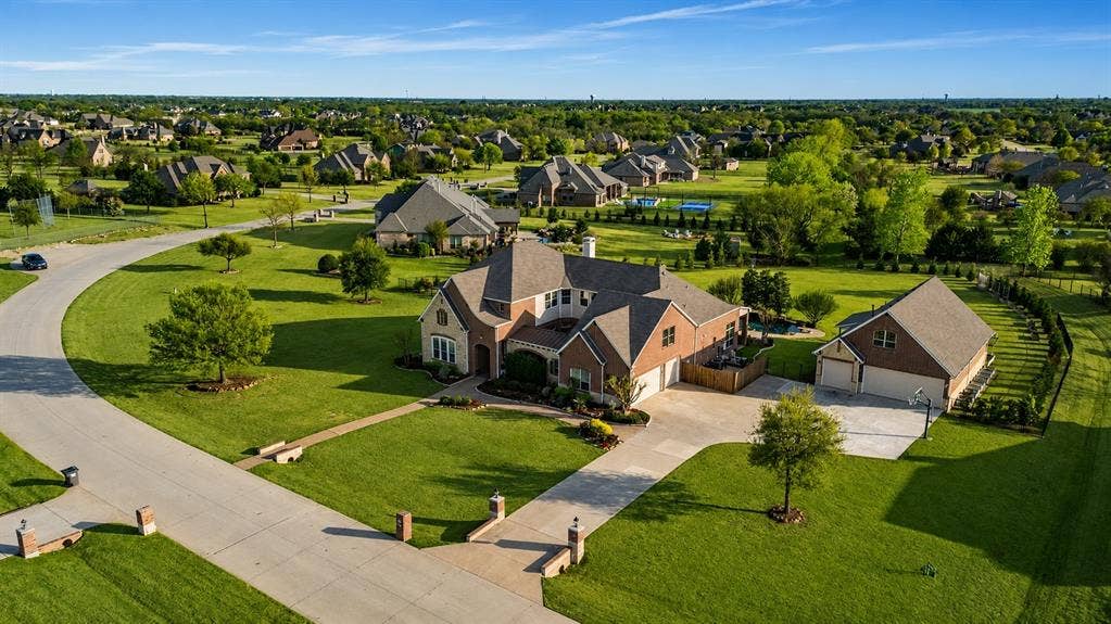 Spacious residential property featuring a brick and stone exterior, a concrete driveway, and an attached two-car garage