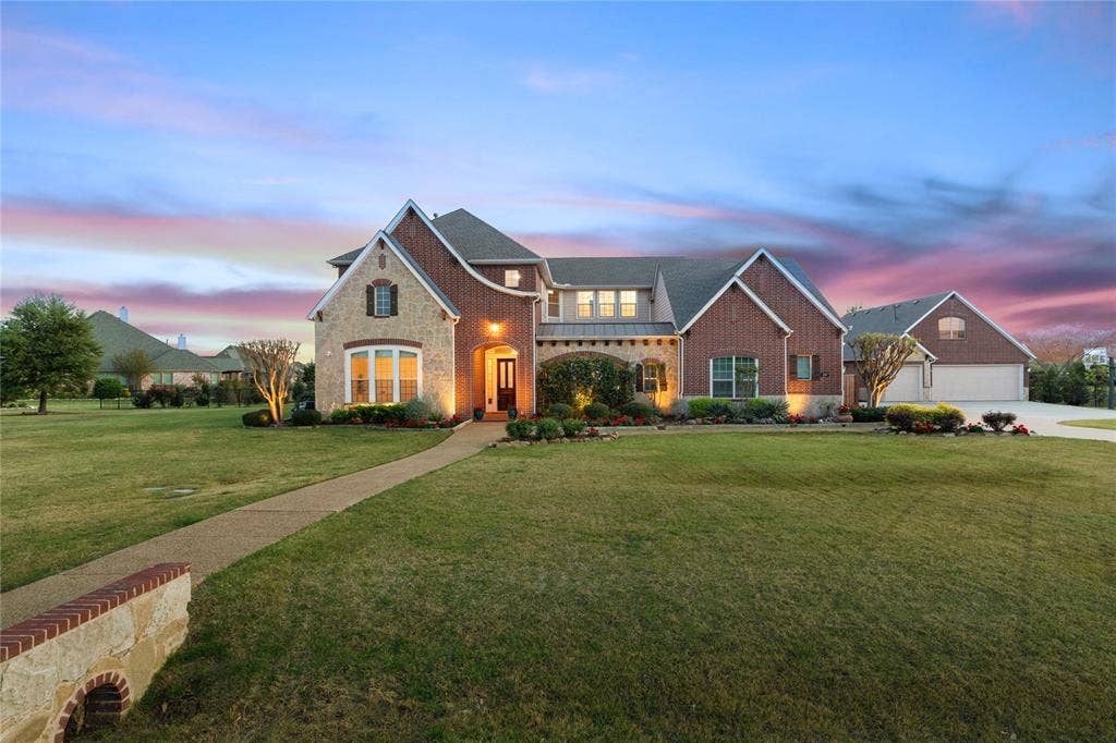 French country inspired facade with a lawn, stone siding, and brick siding