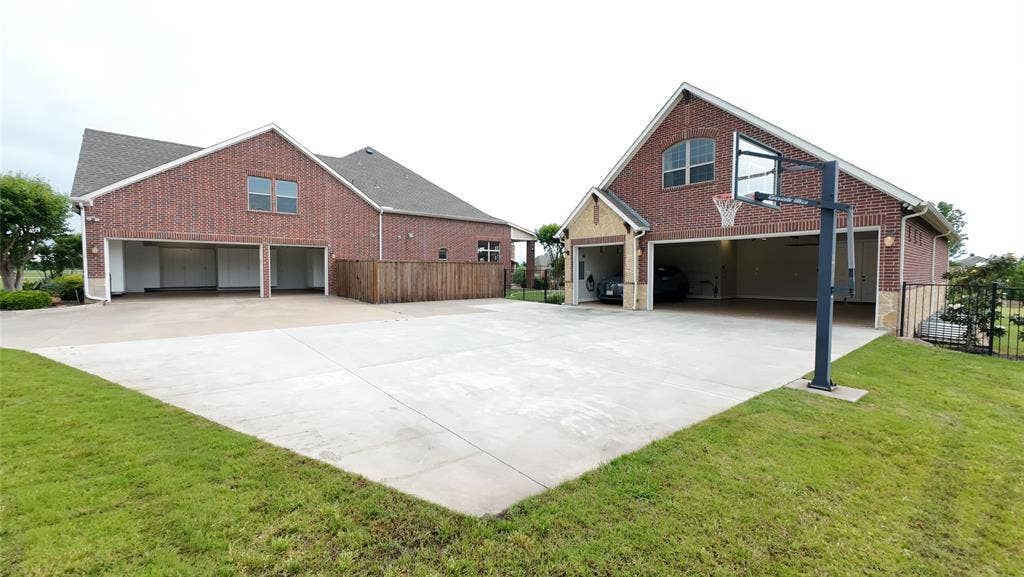 Expansive concrete drive and activity pad featuring a basketball hoop