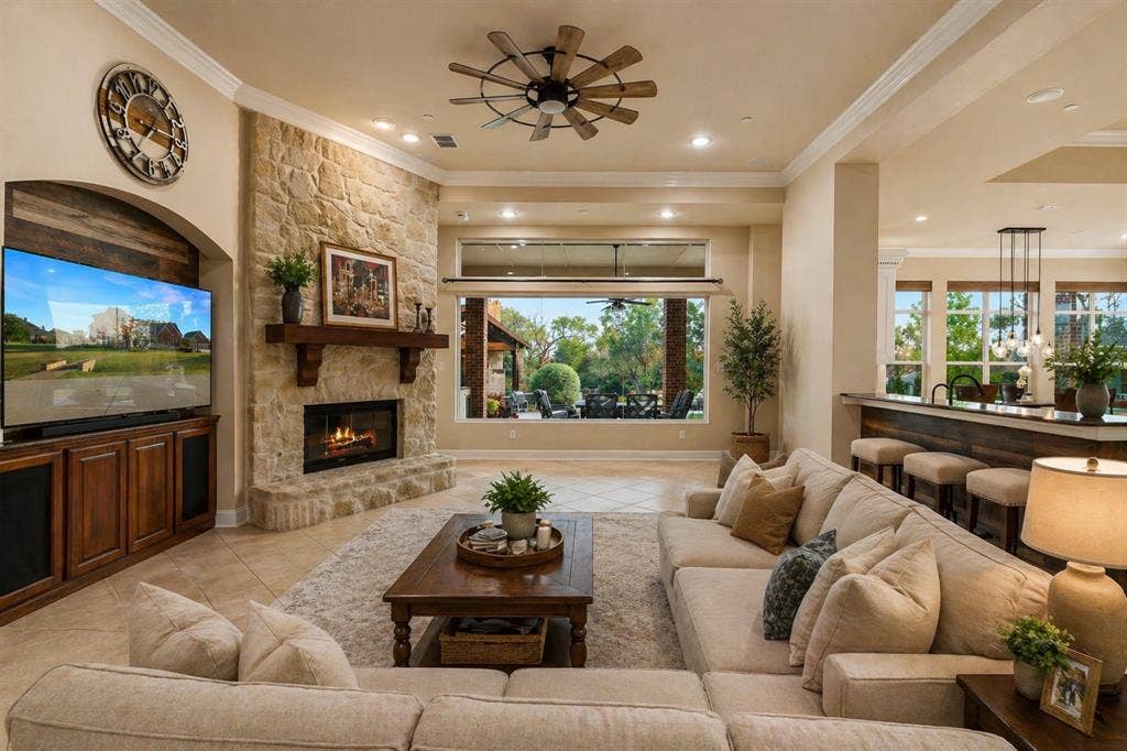 Virtually Staged living room featuring a stone-clad fireplace with a wood mantel, tile flooring, and crown molding.