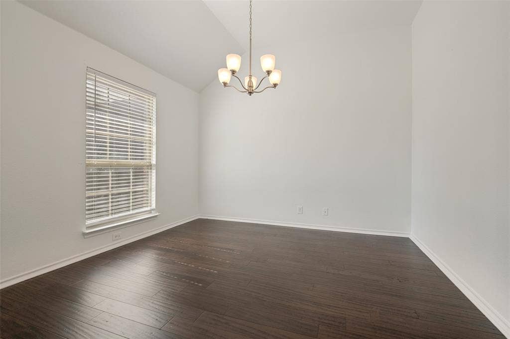 Vaulted ceiling room featuring wood-finish flooring, a chandelier with frosted glass shades, and a large window with horizontal blinds