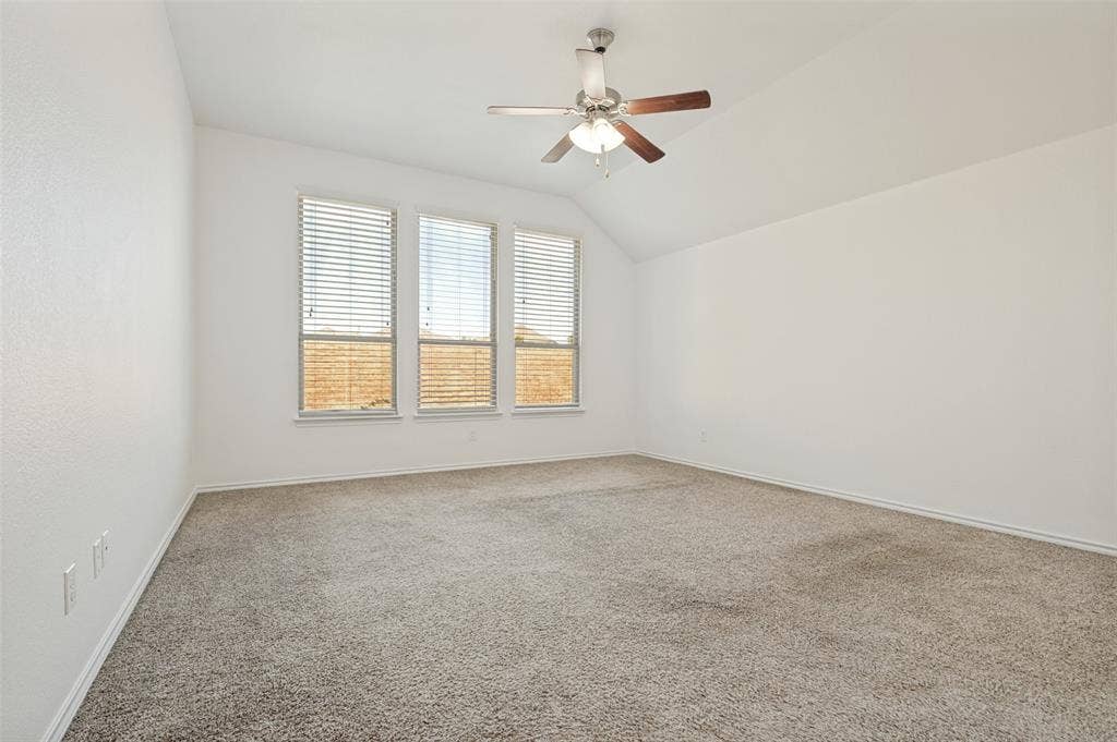 Spacious room featuring vaulted ceilings, neutral carpet, and white walls