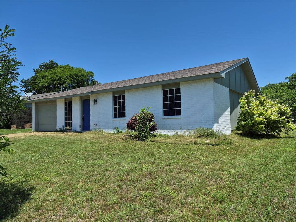 117 Yorkshire Drive, Cedar Hill, TX 75104 White brick exterior featuring a blue entry door, an attached garage, and a gabled roofline