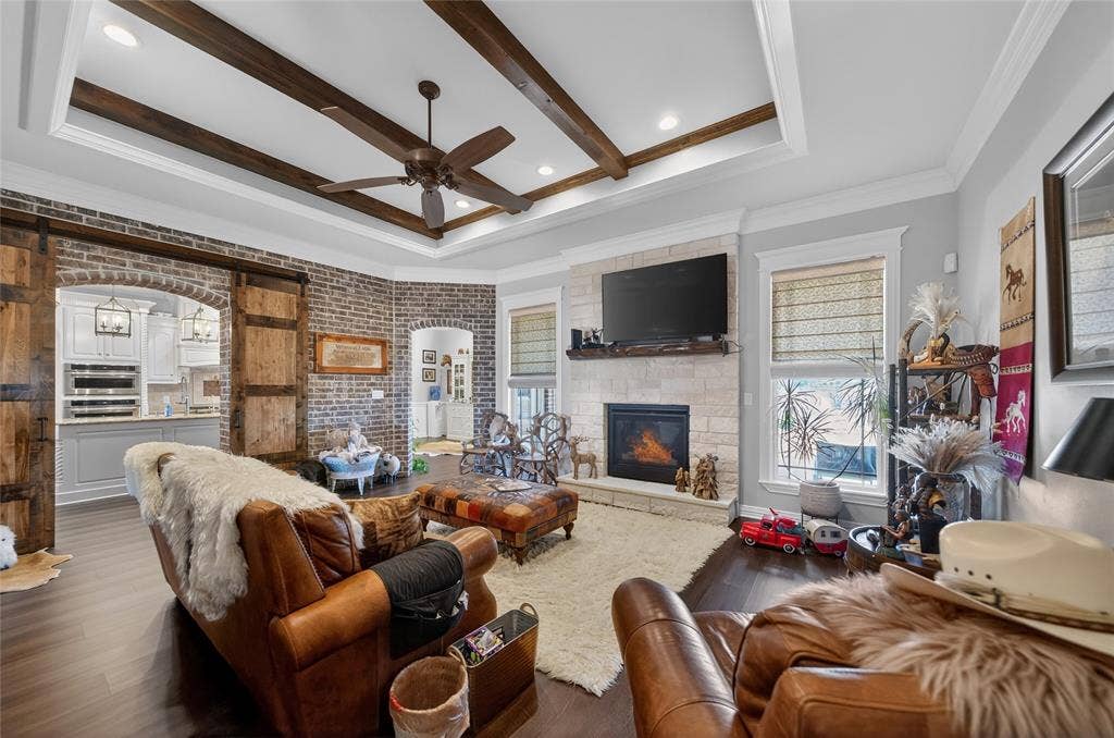 23151 Champion Drive, Lindale, TX 75771 Living room featuring a fireplace, brick wall, arched walkways, ceiling fan, and wood finished floors