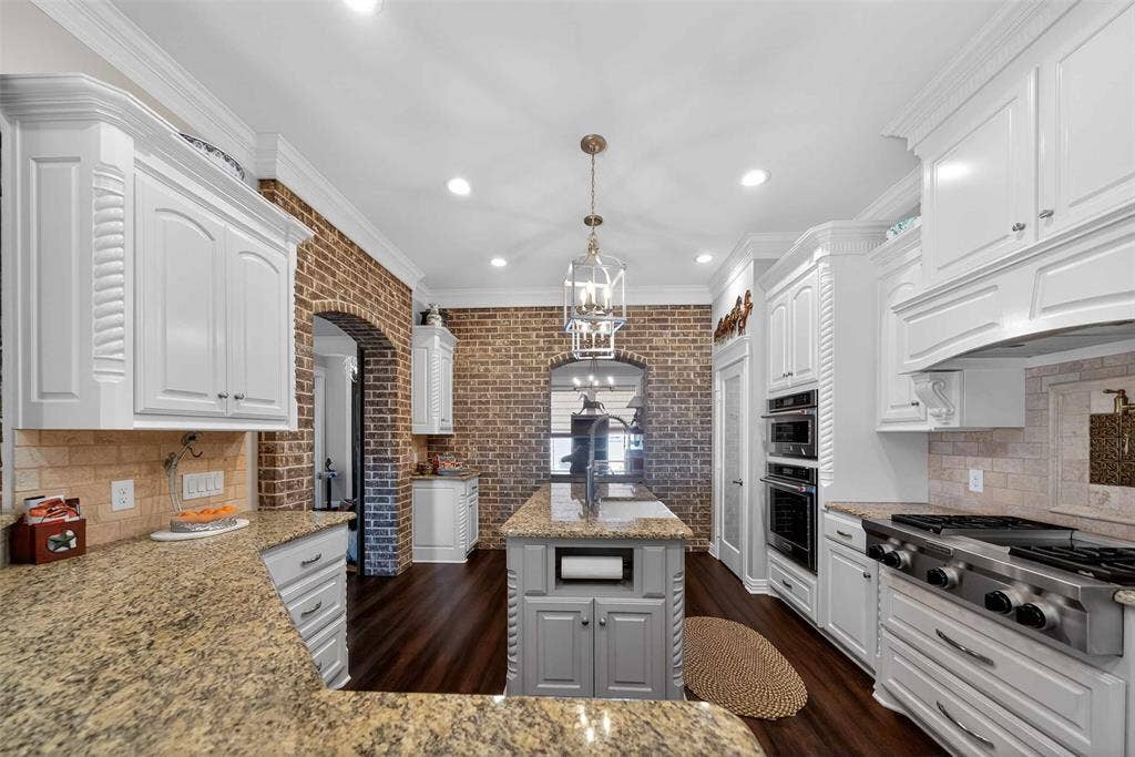 23151 Champion Drive, Lindale, TX 75771 Kitchen with crown molding, backsplash, stainless steel gas stovetop, white cabinetry, and light stone countertops