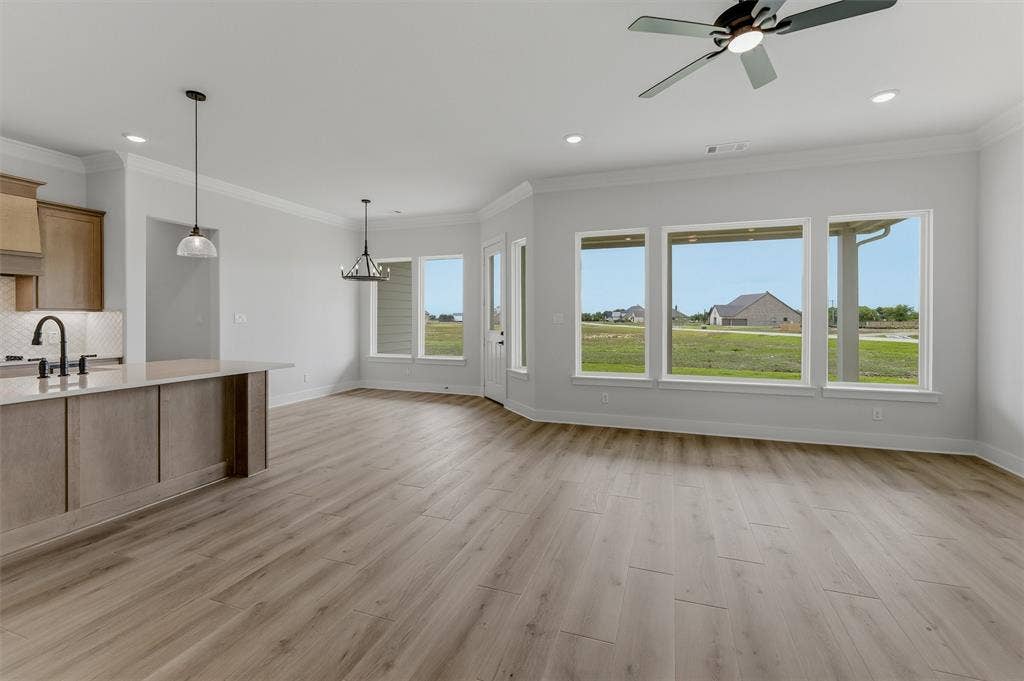 2204 Continent Court, Krum, TX 76249 Spacious room featuring wood-finish flooring, a contemporary ceiling fan, and multiple large windows