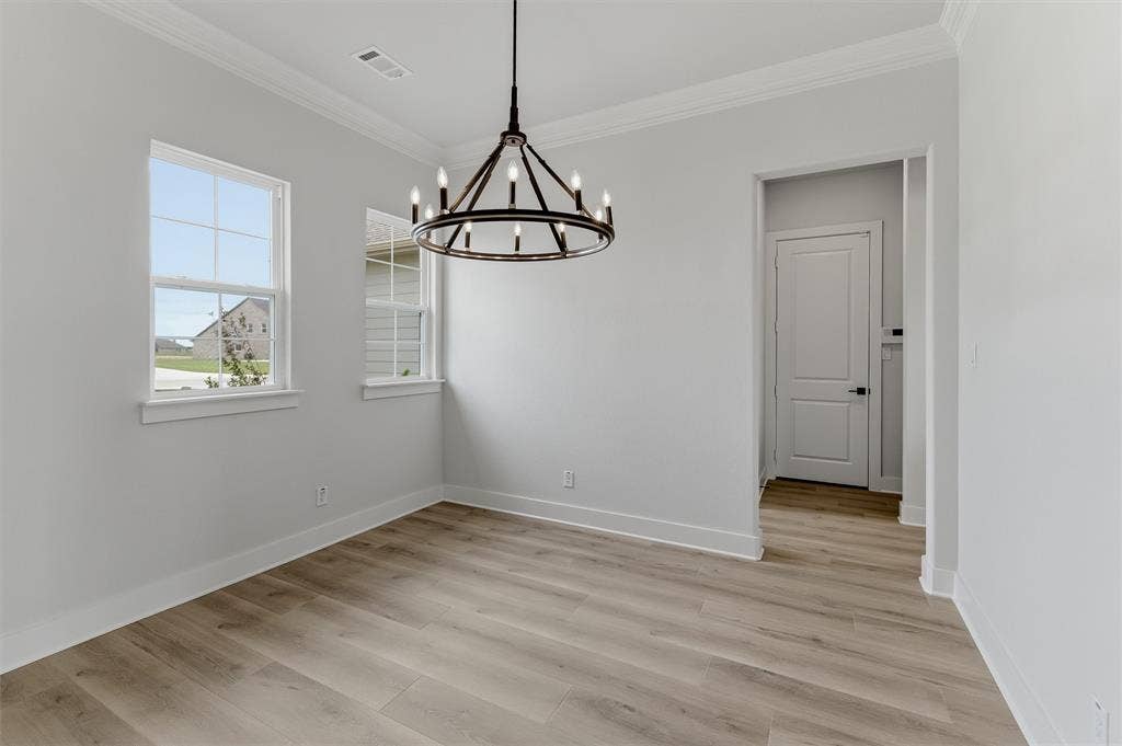 2204 Continent Court, Krum, TX 76249 Room featuring wood-finish flooring, two windows with white trim, a contemporary black metal chandelier, and a doorway with a panel door